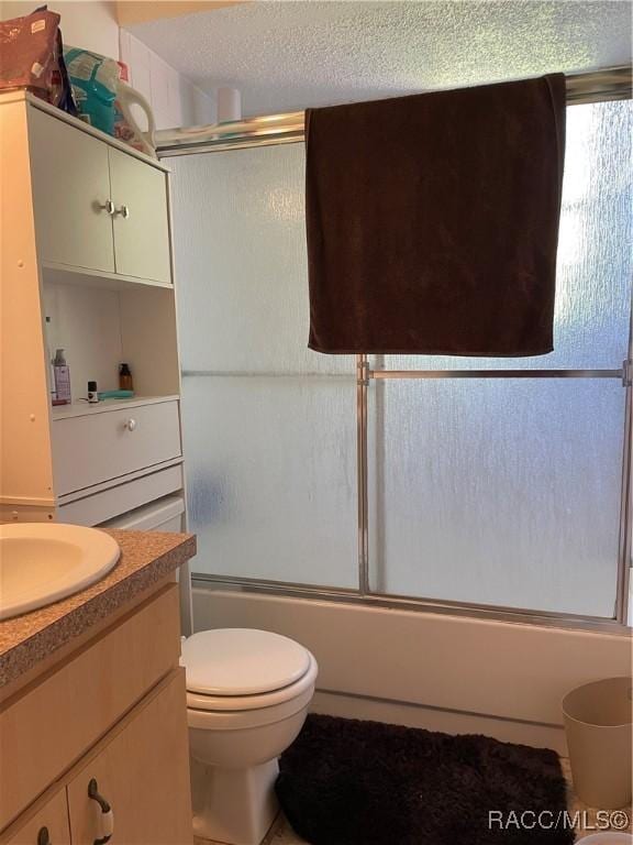 full bathroom featuring enclosed tub / shower combo, toilet, a textured ceiling, and vanity