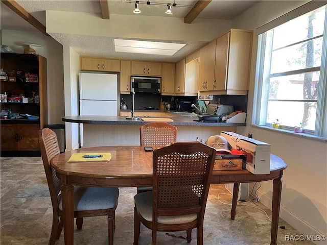 kitchen featuring dark countertops, freestanding refrigerator, cream cabinets, black microwave, and beam ceiling