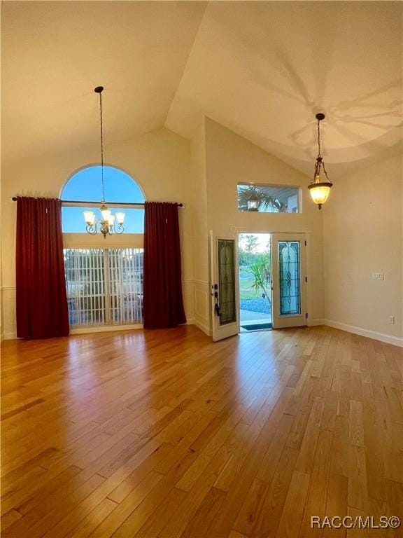 interior space with a chandelier, high vaulted ceiling, wood finished floors, and a wealth of natural light