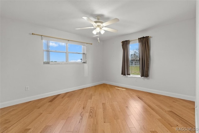 spare room with ceiling fan, light wood-style flooring, and baseboards