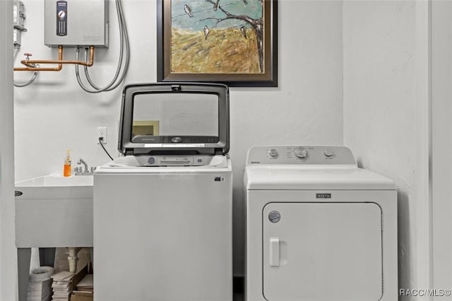 clothes washing area with laundry area, independent washer and dryer, and a sink