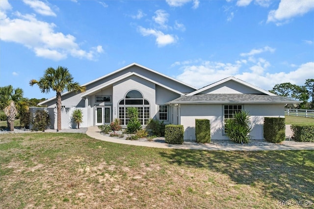 view of front of property with stucco siding, fence, french doors, and a front yard