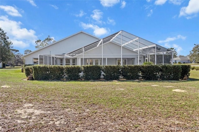 back of property featuring glass enclosure and a yard