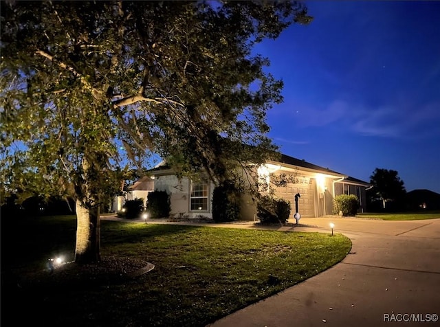 obstructed view of property with driveway, an attached garage, a lawn, and stucco siding