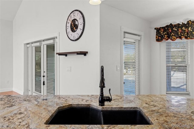 kitchen featuring a sink and light stone countertops