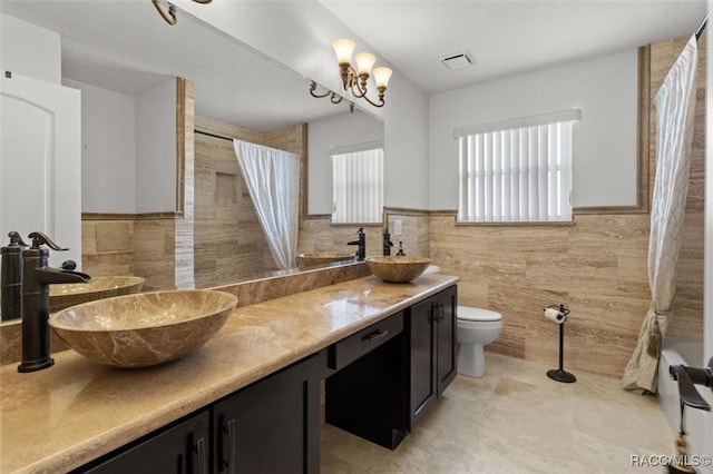 bathroom featuring toilet, tile walls, and a sink