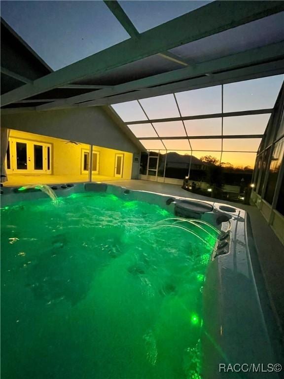 pool at dusk with a patio area, glass enclosure, ceiling fan, and a swimming pool