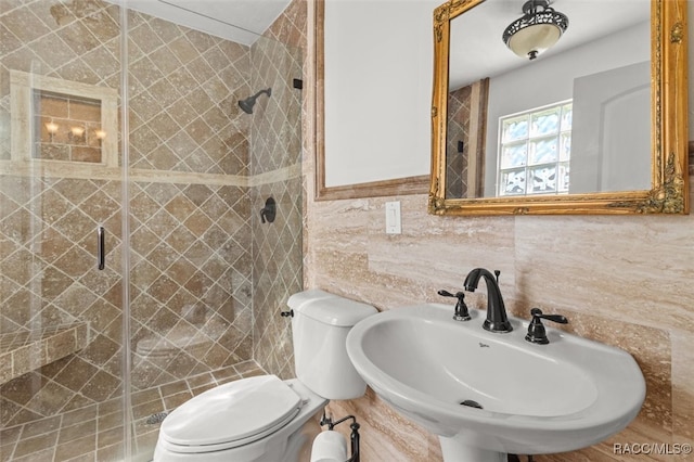 bathroom with toilet, a shower stall, tile walls, and a sink