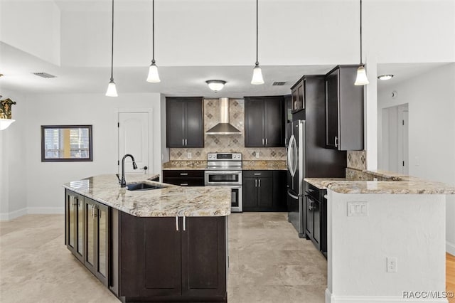 kitchen featuring stainless steel appliances, visible vents, backsplash, a sink, and wall chimney range hood