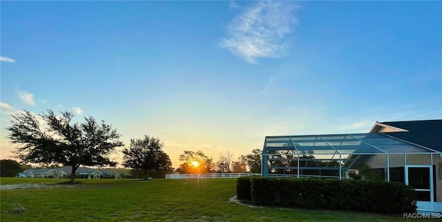 yard at dusk featuring glass enclosure