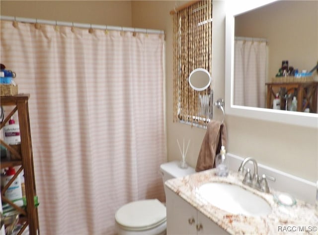 bathroom with vanity, curtained shower, and toilet