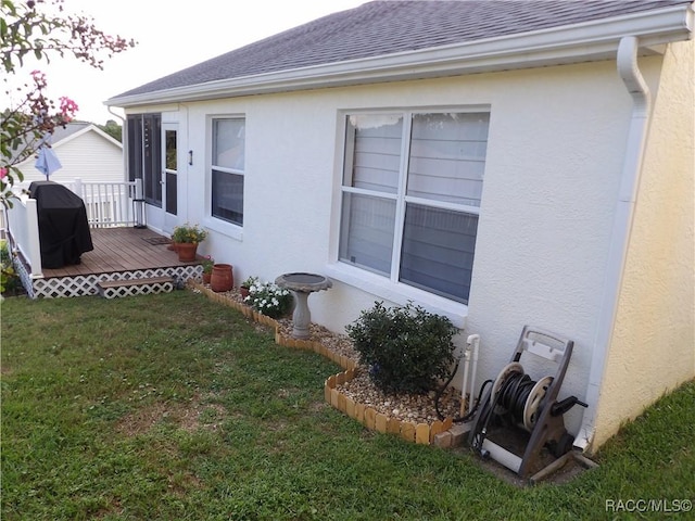 view of side of home with a wooden deck and a lawn