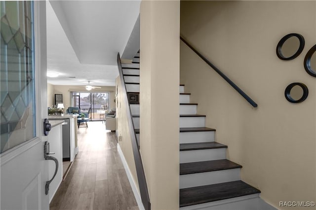 stairs featuring ceiling fan and hardwood / wood-style flooring