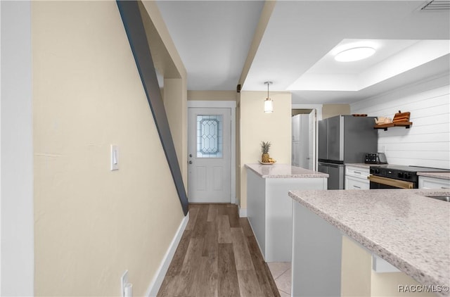 kitchen featuring tasteful backsplash, light hardwood / wood-style floors, stainless steel refrigerator, black electric range oven, and hanging light fixtures