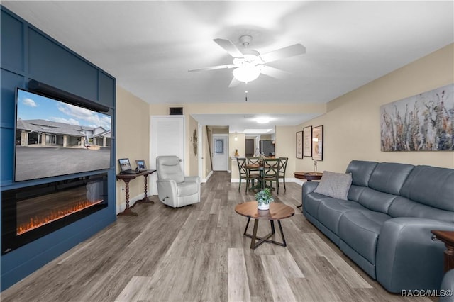 living room with hardwood / wood-style flooring, ceiling fan, and a fireplace