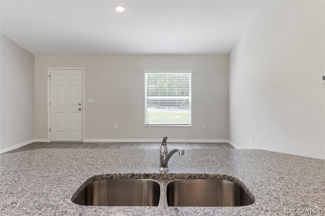 kitchen featuring hardwood / wood-style floors, light stone counters, and sink