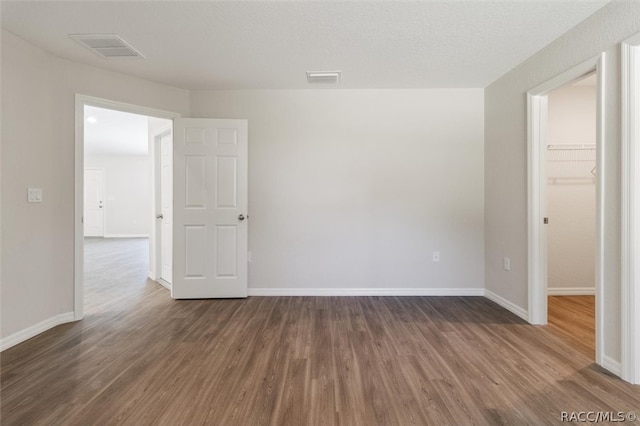 empty room featuring a textured ceiling and dark hardwood / wood-style floors