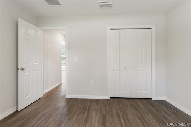 unfurnished bedroom with dark hardwood / wood-style floors and a closet