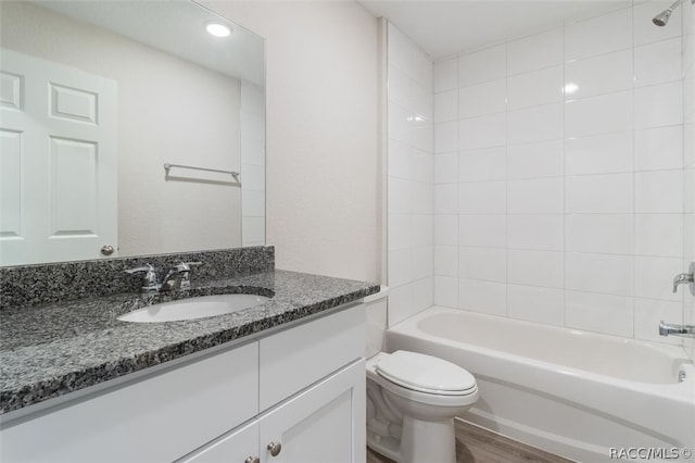 full bathroom featuring tiled shower / bath combo, toilet, wood-type flooring, and vanity