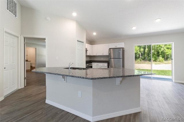 kitchen with white cabinets, a kitchen bar, sink, and stainless steel refrigerator