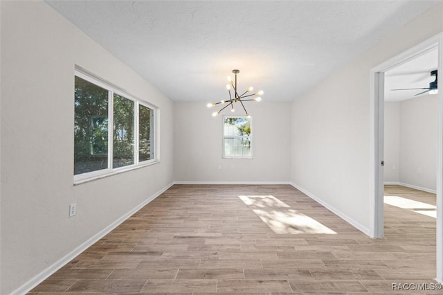 unfurnished dining area with light hardwood / wood-style flooring and ceiling fan with notable chandelier