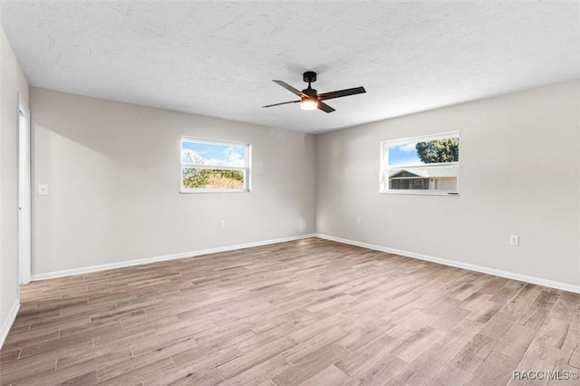 spare room featuring ceiling fan, light wood-type flooring, and a textured ceiling