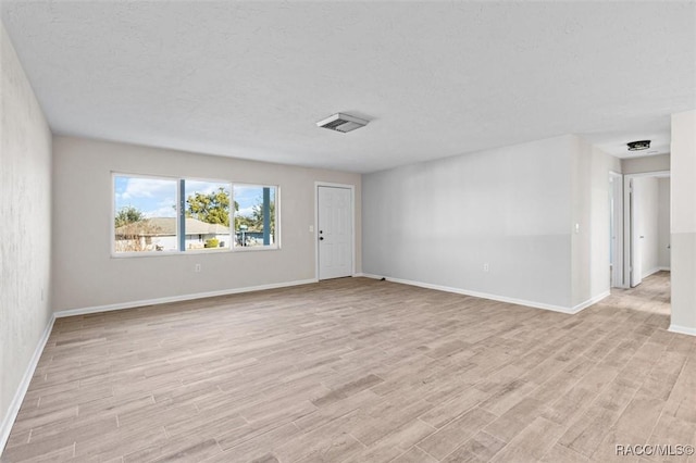 spare room with a textured ceiling and light hardwood / wood-style flooring