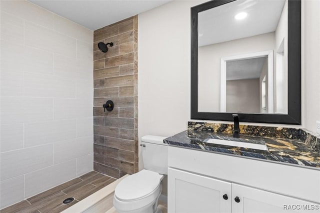 bathroom with vanity, toilet, and a tile shower