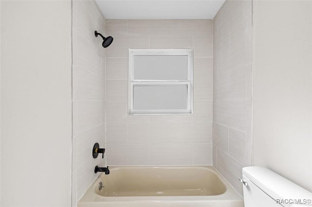 bathroom with toilet and tiled shower / bath