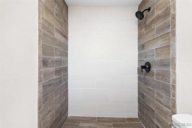 bathroom with tiled shower and toilet