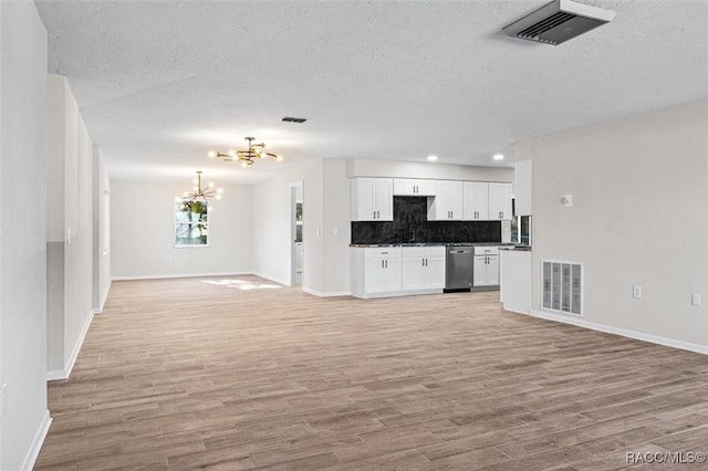 kitchen featuring light wood-type flooring, tasteful backsplash, dishwasher, a chandelier, and white cabinetry