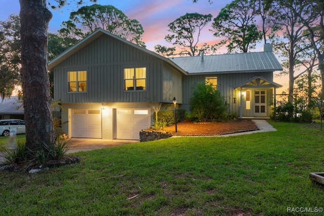 back house at dusk featuring a yard and a garage