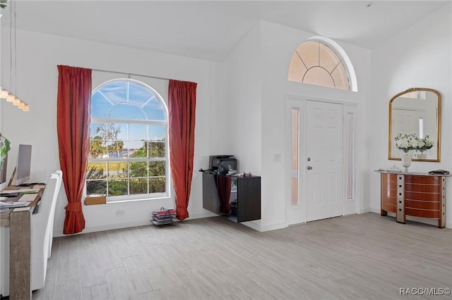 entrance foyer with a healthy amount of sunlight, light wood-type flooring, and baseboards