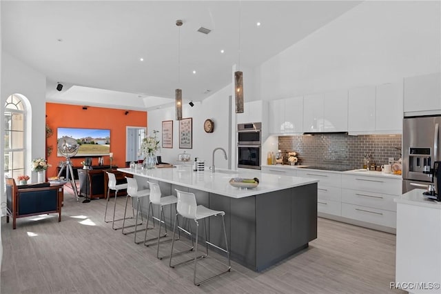 kitchen featuring white cabinetry, light countertops, a large island, appliances with stainless steel finishes, and modern cabinets