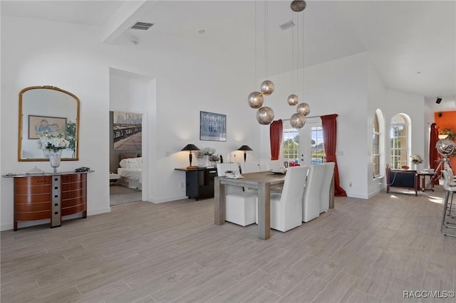 kitchen with a towering ceiling, baseboards, visible vents, light wood-type flooring, and pendant lighting