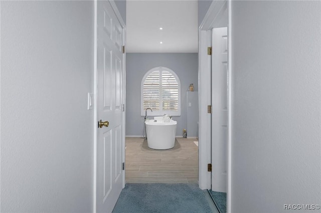 corridor featuring baseboards and light colored carpet