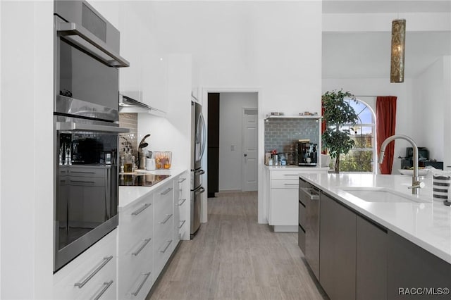 kitchen with pendant lighting, light countertops, white cabinetry, a sink, and modern cabinets