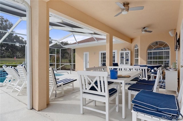 view of patio with a lanai, outdoor dining area, and a ceiling fan