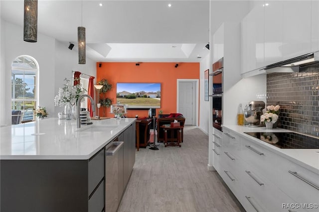 kitchen featuring stainless steel appliances, white cabinetry, a center island with sink, modern cabinets, and decorative light fixtures