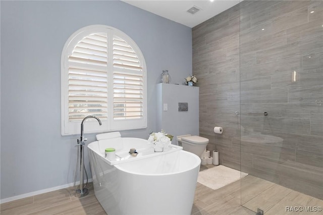 full bathroom with baseboards, visible vents, toilet, a freestanding tub, and a walk in shower