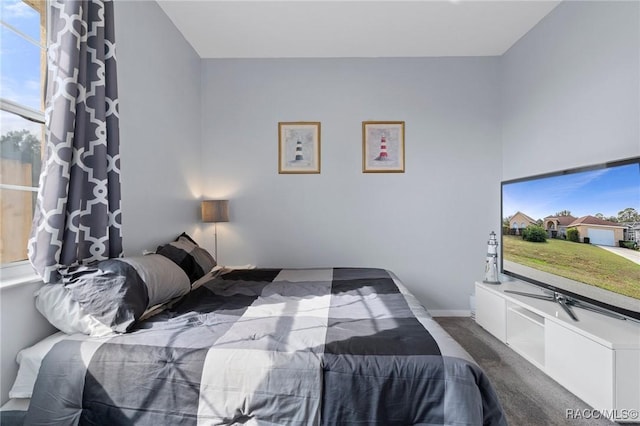 bedroom with dark colored carpet and baseboards