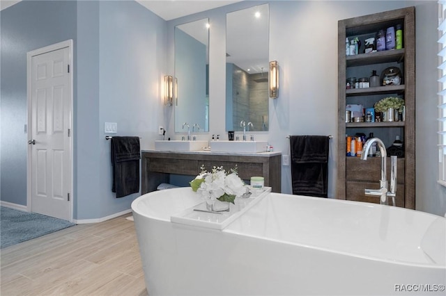 full bathroom featuring a freestanding bath, wood finished floors, vanity, and baseboards