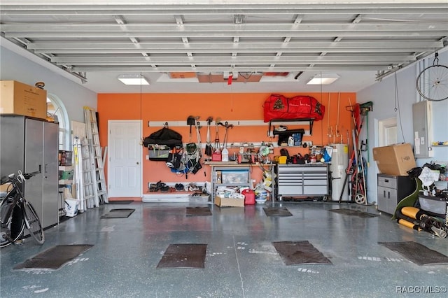 garage featuring electric panel, electric water heater, and a workshop area