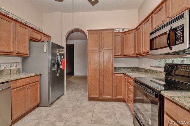 kitchen featuring light stone countertops, stainless steel appliances, and light tile patterned floors