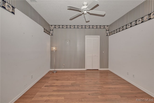 spare room featuring ceiling fan, wood-type flooring, and a textured ceiling