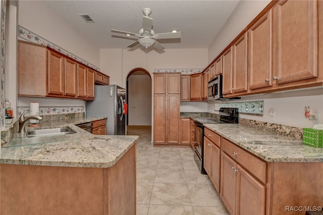 kitchen with kitchen peninsula, appliances with stainless steel finishes, light stone counters, a textured ceiling, and sink