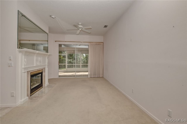 unfurnished living room featuring ceiling fan, light colored carpet, and a fireplace