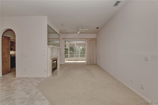 unfurnished living room with ceiling fan, a premium fireplace, and light carpet