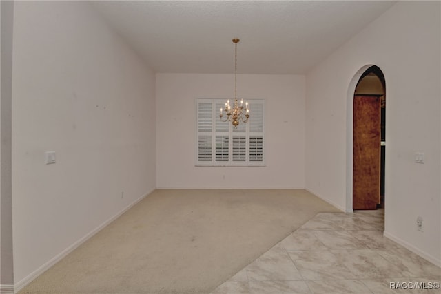 carpeted spare room featuring a notable chandelier