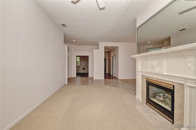 unfurnished living room with a textured ceiling, ceiling fan, a fireplace, and carpet